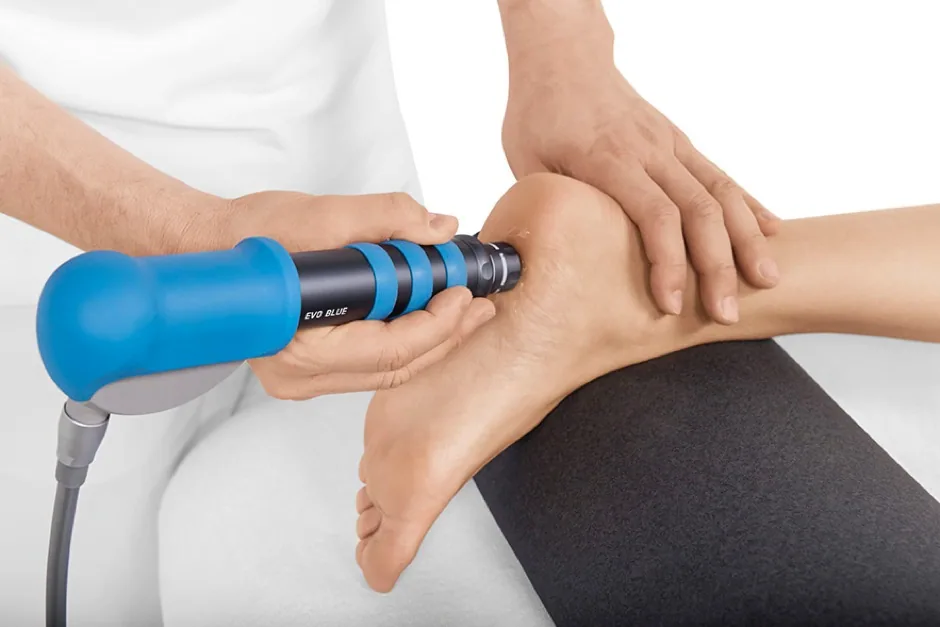 Therapist applying extracorporeal shock wave therapy to a patient's ankle